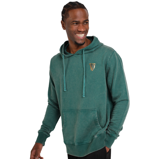 A man wearing a Guinness Forest Green & Gold Toucan Hoodie with the Ireland crest on it.