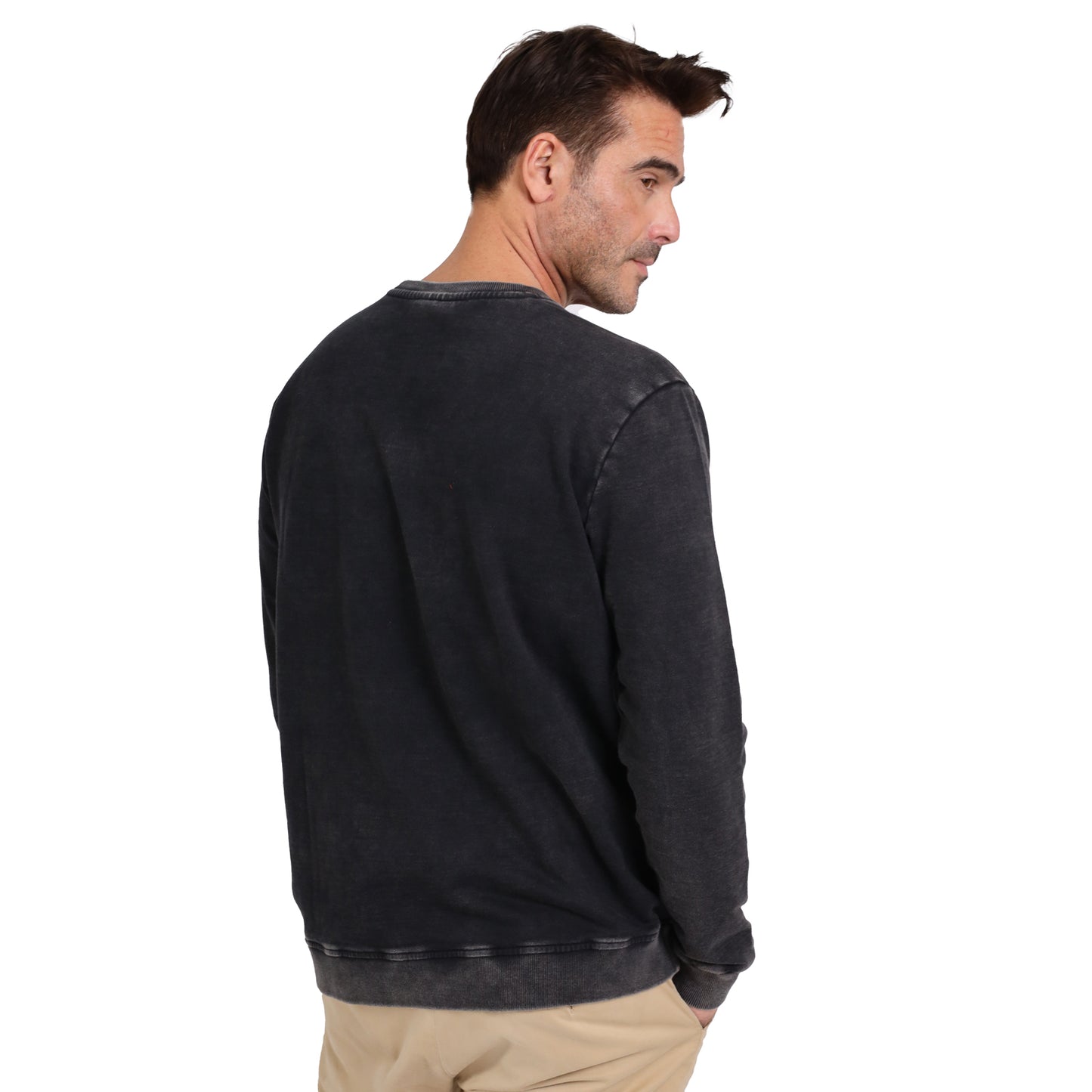 A man in a dark Guinness Metallic Print Trademark Sweatshirt from Guinness Webstore UK and light khaki pants stands with his back to the camera, glancing over his shoulder.