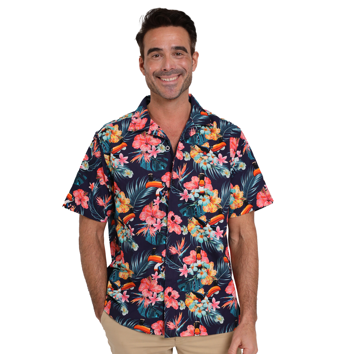 A man wearing a dark Guinness Toucan Hawaiian Shirt and tan pants smiles at the camera, evoking tropical paradise vibes as he poses against a white background.