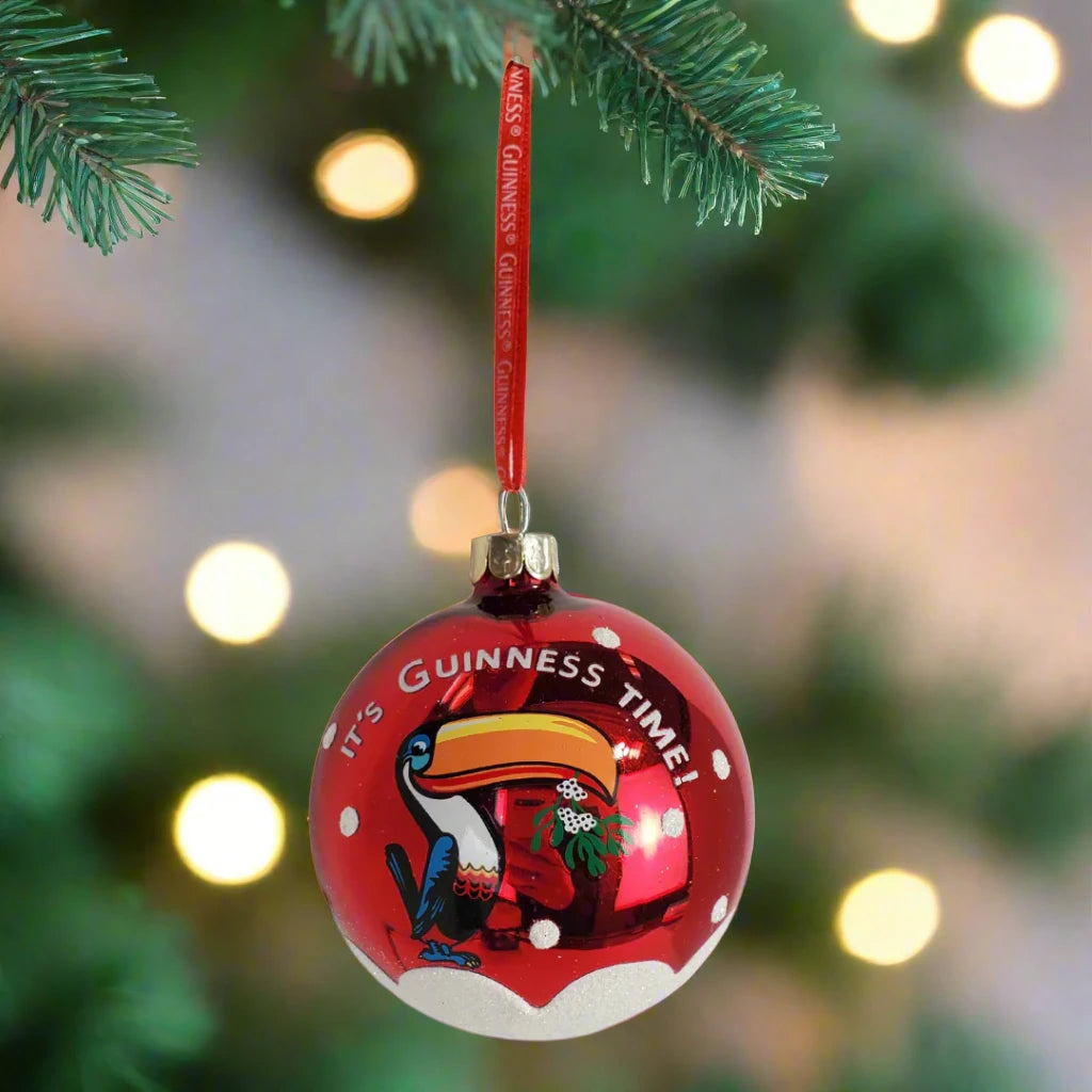 The Guinness Christmas Toucan Bauble showcases a vibrant design featuring the iconic toucan with "It's Guinness Time!" inscribed. It comes with a red ribbon for easy hanging, making it the perfect festive touch.