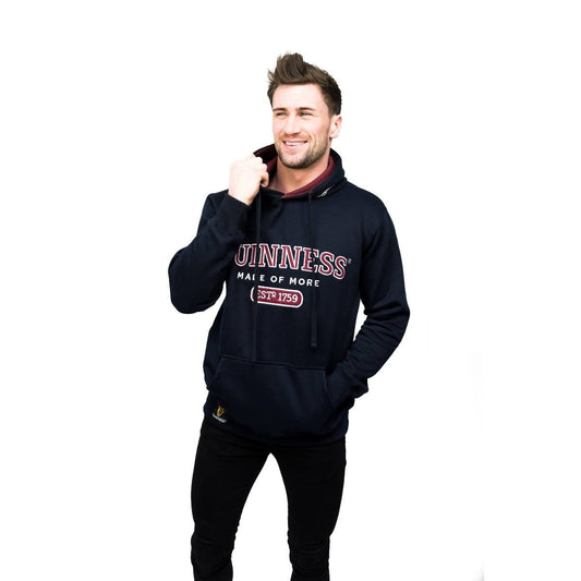 A young man wearing a Guinness UK Signature Navy Hooded Sweatshirt featuring the Guinness logo.
