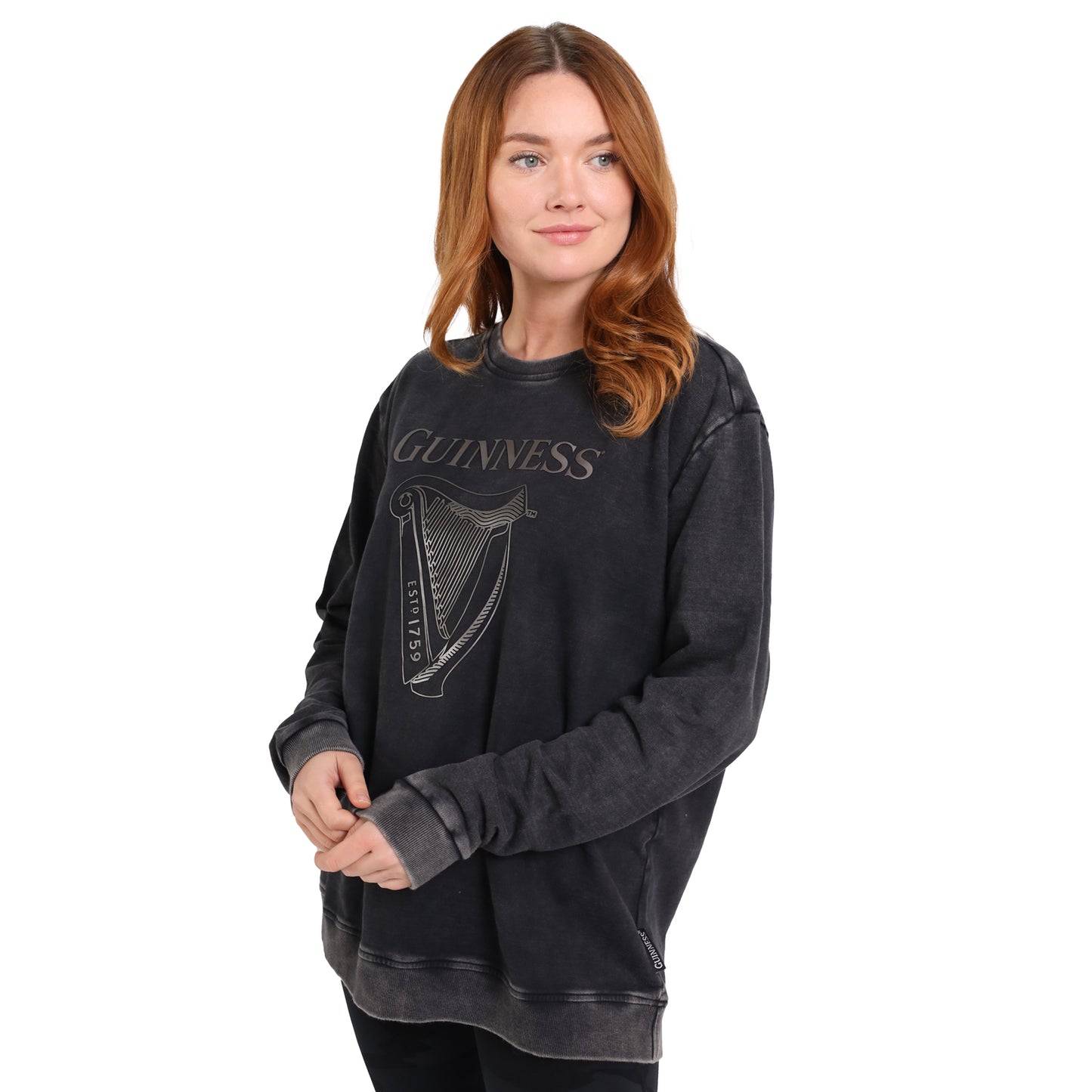 A woman wears the Guinness Metallic Print Trademark Sweatshirt by Guinness Webstore UK, made from sustainable cotton with a metallic harp logo, standing against a white background.