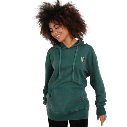 A woman wearing a Guinness Forest Green & Gold Toucan Hoodie and smiling.