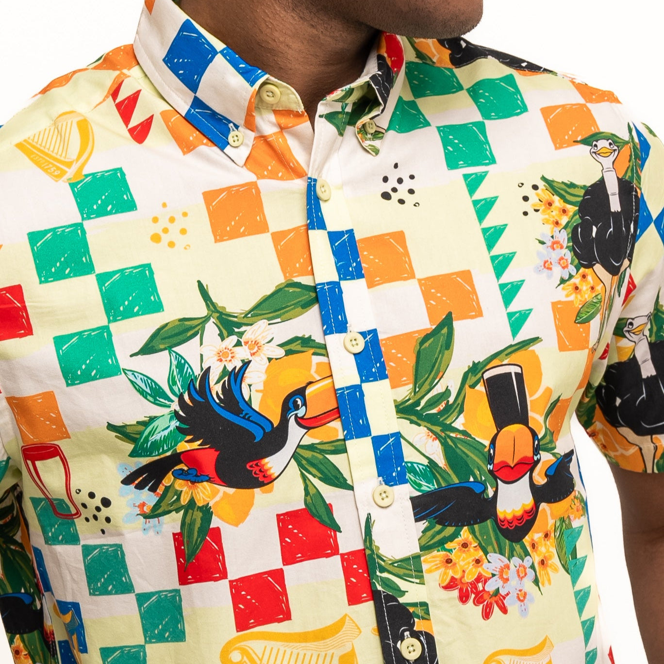 A man wears the Guinness Toucan Beach Shirt from Guinness Webstore UK, a Hawaiian-style short-sleeve button-up featuring colorful tropical birds and patterns on breathable woven cotton.