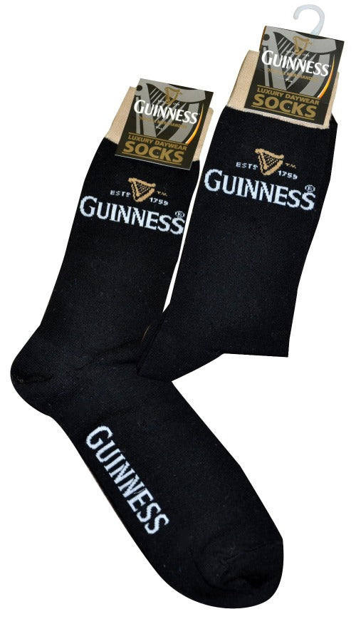 A pair of black Guinness Signature Pint Socks hanging on a hook, each featuring gold accents and the Guinness logo.