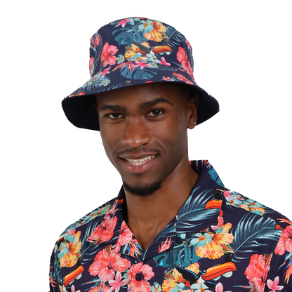 A person wearing a floral patterned Guinness Hawaiian Reversible Bucket Hat from Guinness Webstore UK and matching shirt smiles at the camera.