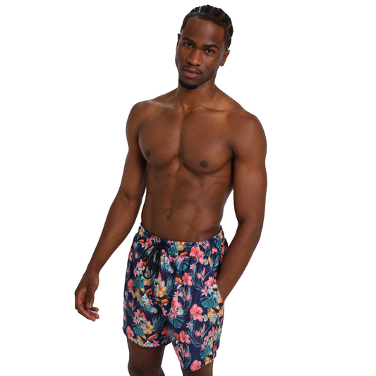 A man with braided hair poses shirtless in Guinness Toucan Hawaiian Beach Shorts from Guinness Webstore UK, made from eco-friendly fabric, against a white background.