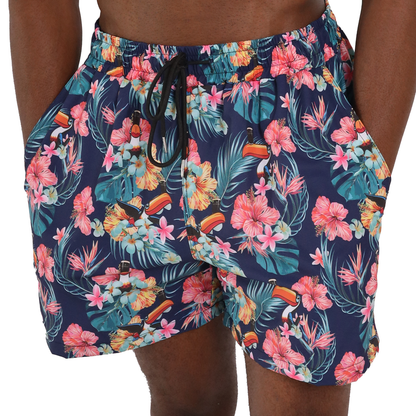 A person wearing Guinness Toucan Hawaiian Beach Shorts by Guinness Webstore UK, featuring vibrant pink, orange, and yellow flowers and green leaves.