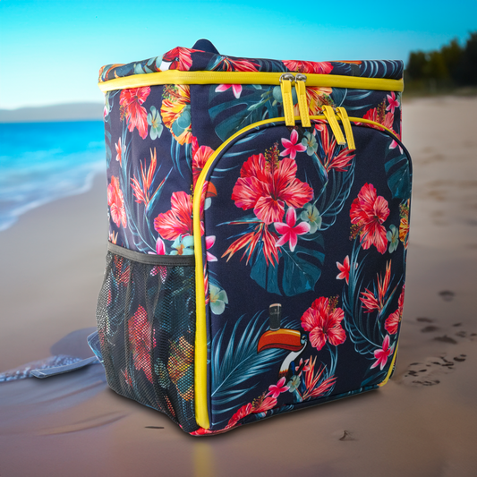 A floral-patterned backpack with yellow zippers rests on a sandy beach, surrounded by the calming ocean and vibrant sky. Nearby, a Guinness Toucan Hawaiian Cooler Bag from Guinness Webstore UK adds an extra touch of tropical charm to this picturesque setting.