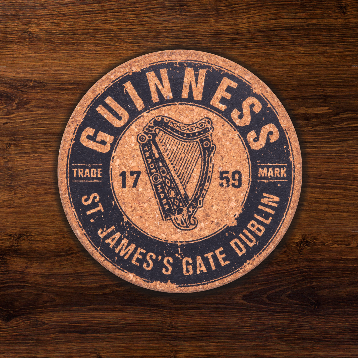 The Guinness Harp Cork Coaster Set (4 Pack) features a black "Guinness" logo and harp on round coasters, surrounded by "St. James's Gate Dublin" and "Trade Mark 1759." This official merchandise is ideal for fans of branded cork coasters.