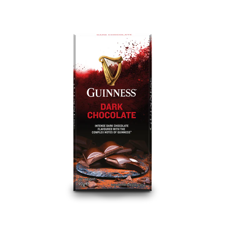 The packaging of the Guinness Luxury Dark Chocolate Bar showcases a peeling chocolate bar alongside the iconic Guinness logo, accompanied by the description "Intense dark chocolate flavored with the complex notes of Guinness." This luxurious treat is elegantly offered in a 90g bar, ideal for those desiring indulgence.