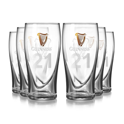 The Guinness Pint Glasses - 6 Pack from Guinness UK features an embossed harp and the number "21," with a unique curved base design. The iconic gold harp logo adds elegance, making it ideal for beer enthusiasts.