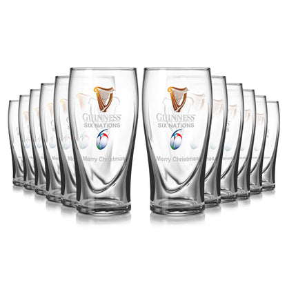 The Guinness Six Nations Pint Glass - 12 Pack showcases twelve clear glasses, each featuring the tournament logo and festive "Merry Christmas" text, ideal for celebrating the Championship.