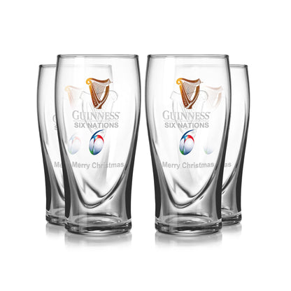 The Guinness Six Nations Pint Glass - 4 Pack includes four clear glasses designed for rugby fans. Each glass features the "Guinness Six Nations" and "Merry Christmas" logo and text, making them perfect festive gifts for sports enthusiasts.