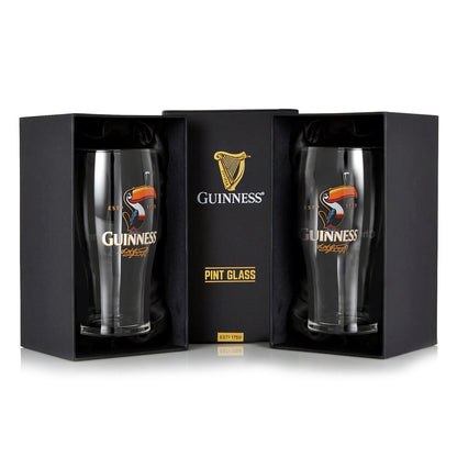 The Guinness Toucan Pint Glass - 2 Pack by Guinness UK includes two glasses with the iconic toucan design, packaged in a sleek black box labeled "Official Guinness Merchandise," perfect for enthusiasts or collectors.