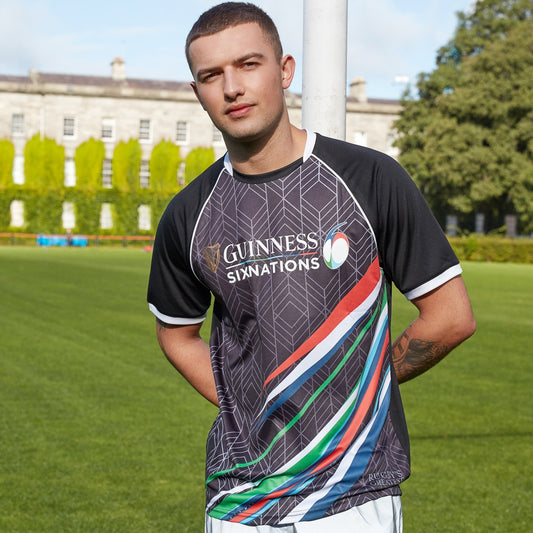 A rugby fan wearing a Guinness 6 Nations Performance T-Shirt, displaying both design and performance, standing on a field.