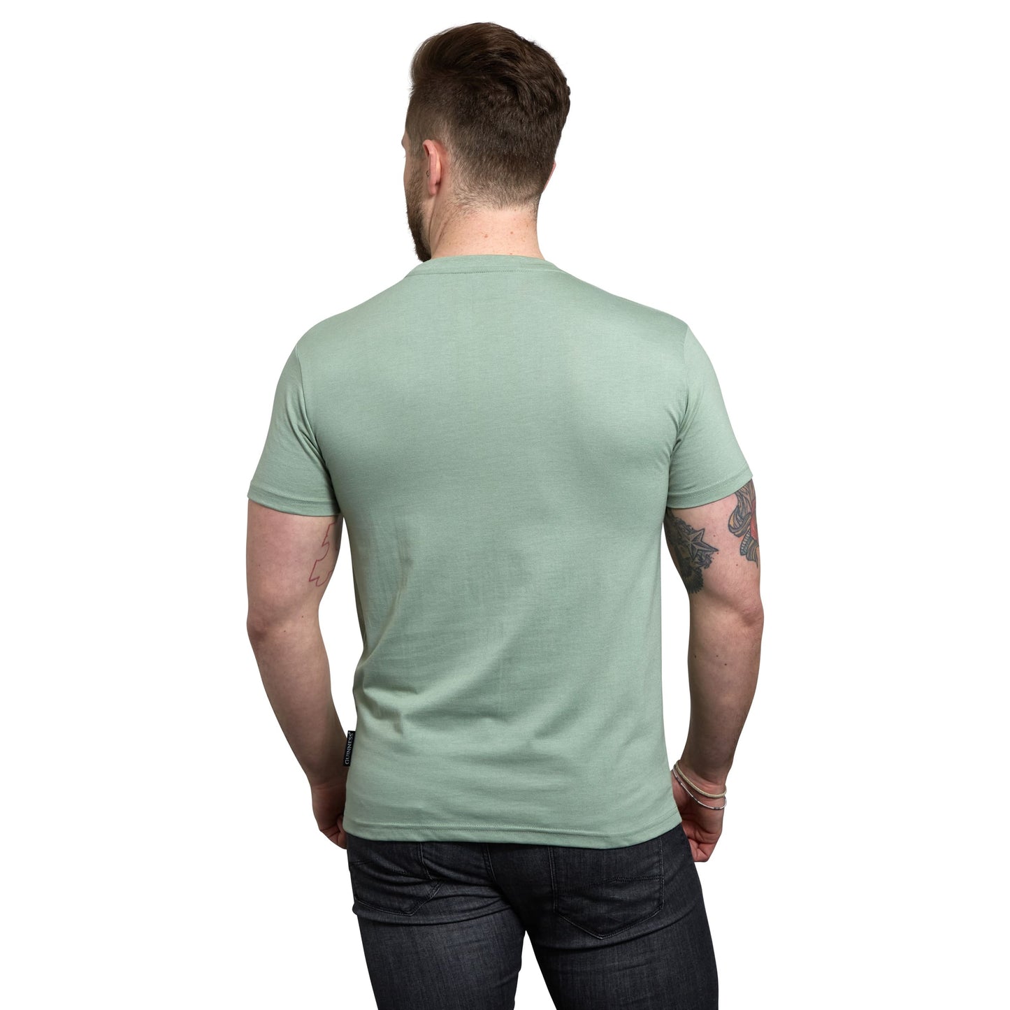 The back view of a man wearing a Guinness Green Bottle Cap T-Shirt with a Guinness bottle cap design.