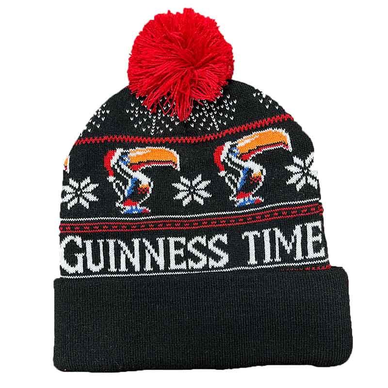 The Guinness Christmas Toucan Beanie, from the renowned Guinness brand, is a festive black hat featuring a red pom-pom. It is decorated with "Guinness Time" text alongside charming toucans and snowflake patterns, making it ideal for the holiday season.