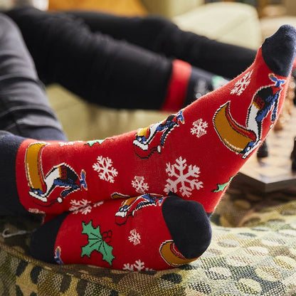 Feet wearing vibrant Guinness Toucan Snowflake Socks from Guinness Webstore UK rest comfortably on a cozy couch.