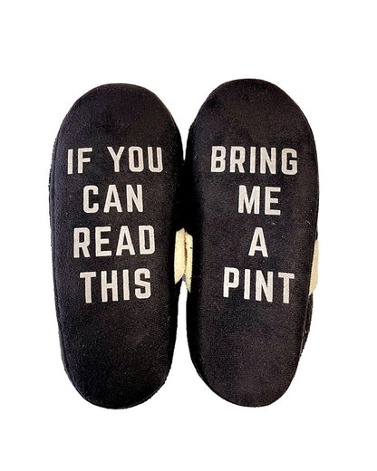 The Guinness Harp Slippers - Bring A Pint feature black fabric with white text that reads "IF YOU CAN READ THIS" on the left slipper and "BRING ME A PINT" on the right. Ideal as a novelty gift for beer lovers, these slippers promise to be the perfect cozy accessory for those who enjoy combining fun with relaxation.