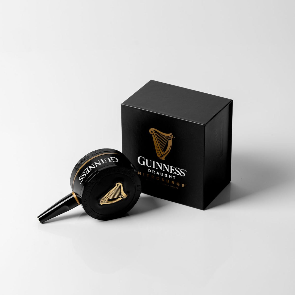 The Guinness Nitrosurge Gift Bundle, offered by Guinness UK, showcases a striking black box with the iconic gold harp logo set against a white backdrop. Enjoy the silky flow of cascading nitrogen bubbles, perfected by an advanced ultrasonic transducer for an ideal pour.