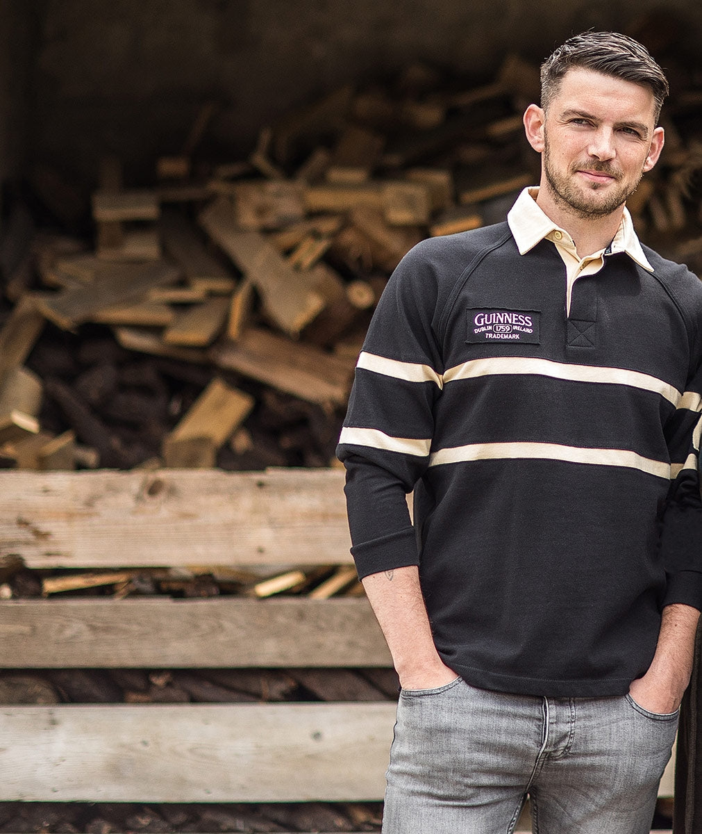 A man and a woman, dressed in Guinness Traditional Rugby Jerseys made of cotton, standing next to a pile of wood.