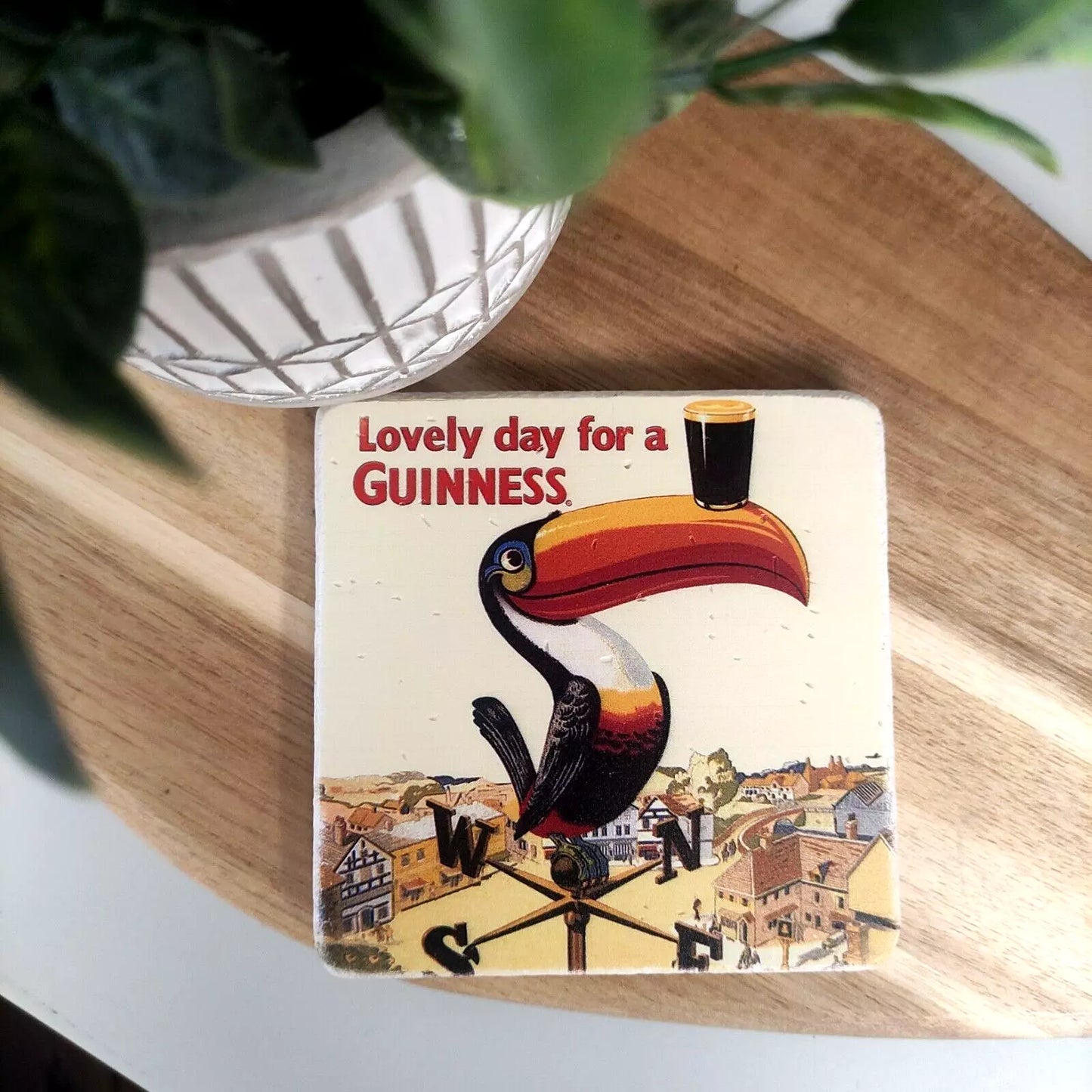 The Guinness Stone Effect Coaster - Gilroy Toucan from the Guinness Webstore UK features the classic Gilroy Toucan design, depicting a colorful toucan skillfully balancing a pint of Guinness on its beak alongside the phrase "Lovely day for a Guinness." It's an ideal choice for any authentic Guinness enthusiast.