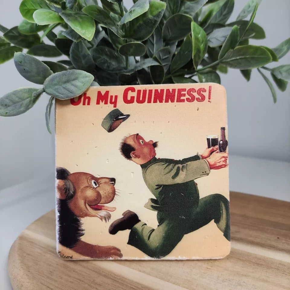 A vintage-style illustration of a Guinness enthusiast, startled by a jubilant dog leaping up, causing them to drop a bottle and glass of Guinness. The text reads "Oh My GUINNESS!" with a plant in the background, evoking the classic Gilroy Lion & Zookeeper design featured on the Guinness Stone Effect Coaster available at Guinness Webstore UK.