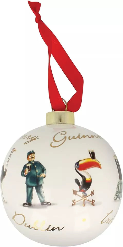 This ceramic Christmas bauble from the Guinness Gilroy Collection is a perfect addition for beer enthusiasts looking to add festive charm. It hangs elegantly with a red ribbon and showcases a man in a blue uniform alongside a toucan, with "Guinness," "Dublin," and "Ireland" written in gold cursive.