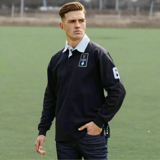 A person stands outside, wearing a Guinness Six Nations Long Sleeve Rugby Jersey from the Guinness Webstore UK, featuring the number 6 on the sleeve. One hand is casually placed in their pocket as they look to the side, capturing the essence of the Guinness Six Nations.